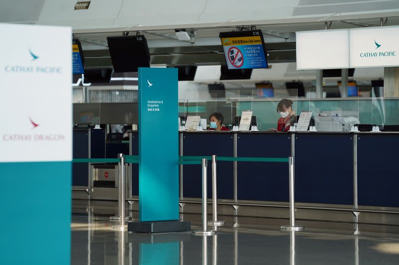 Cathay Pacific employees are seen behind counters with glass dividers at Hong Kong International Airport