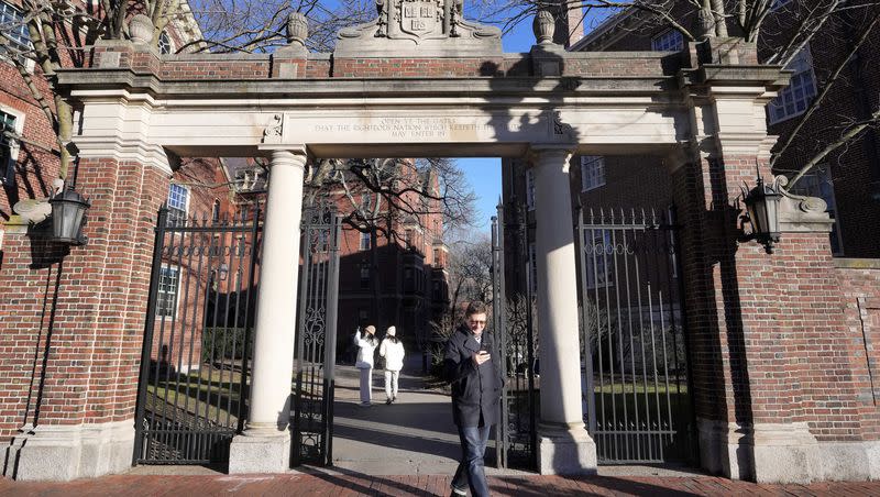 A passer-by walks through a gate to the Harvard University campus on Tuesday, Jan. 2, 2024, in Cambridge, Mass. Harvard University President Claudine Gay resigned Tuesday amid plagiarism accusations and criticism over testimony at a congressional hearing where she was unable to say unequivocally that calls on campus for the genocide of Jews would violate the school’s conduct policy.