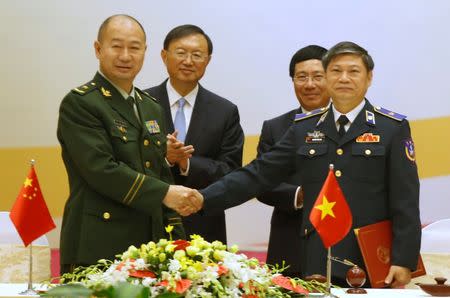 China's Coast Guard deputy chief Wang Hongguang (L) shakes hands with Vietnam's Coast Guard deputy chief Nguyen Van Son (R) after signing a cooperation agreement as China's State Councilor Yang Jiechi (2nd L) and Vietnam's Deputy Prime Minister and Foreign Minister Pham Binh Minh (2nd R) look on at the International Convention Center in Hanoi, Vietnam June 27, 2016. REUTERS/Kham