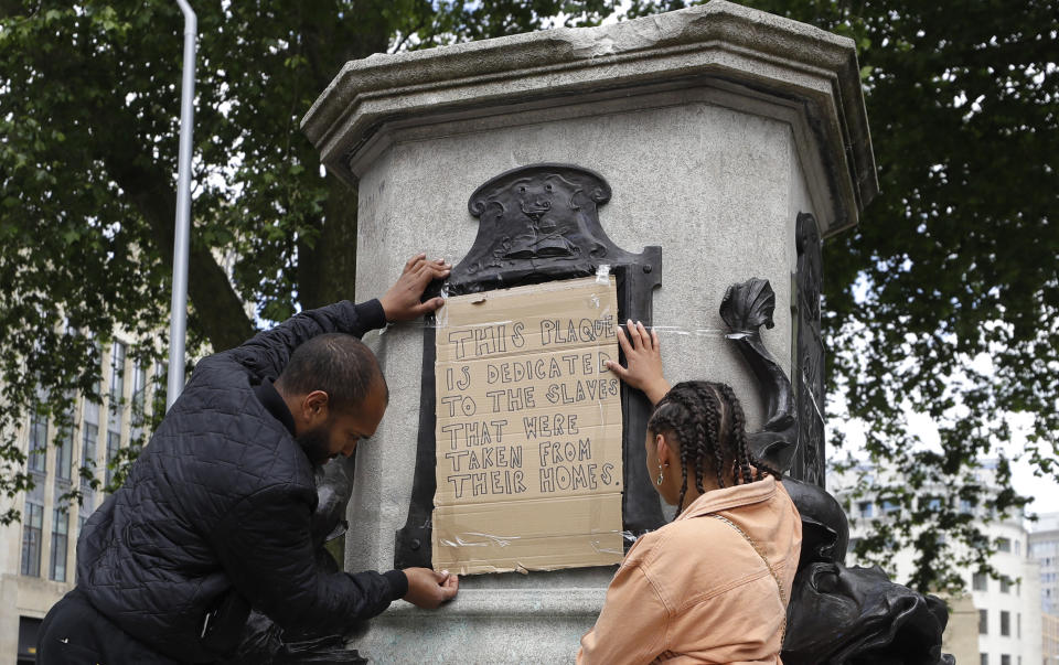 A banner is taped over the inscription on the pedestal of the toppled statue of Edward Colston in Bristol, England, Monday, June 8, 2020. The toppling of the statue was greeted with joyous scenes, recognition of the fact that he was a notorious slave trader — a badge of shame in what is one of Britain’s most liberal cities. (AP Photo/Kirsty Wigglesworth)