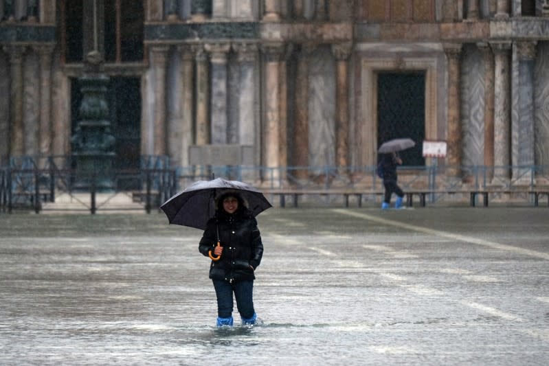 A tourist pose in St. Mark’s Square after days of severe flooding in Venice