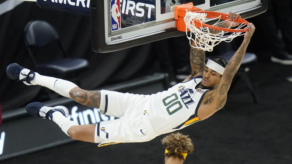 Utah Jazz guard Jordan Clarkson (00) hangs from the rim after dunking against the Golden State Warriors during the first half of an NBA basketball game Saturday, Jan. 23, 2021, in Salt Lake City. (AP Photo/Rick Bowmer)