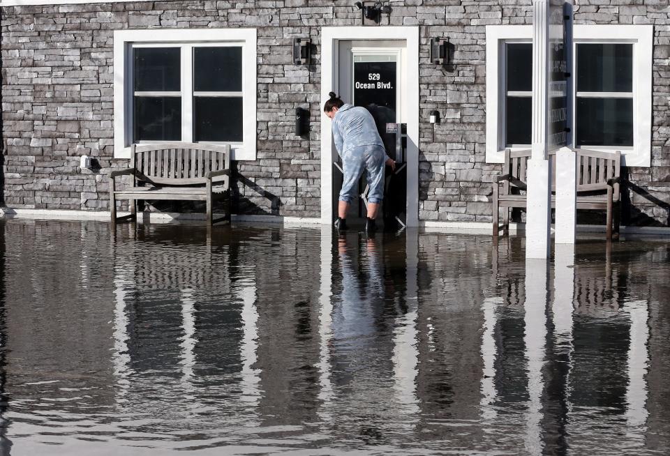 A woman tries to control the flooding at a business at 529 Ocean Boulevard at Hampton Beach as the high tide brings wter over the seawall Wednesday, Jan. 10, 2024.