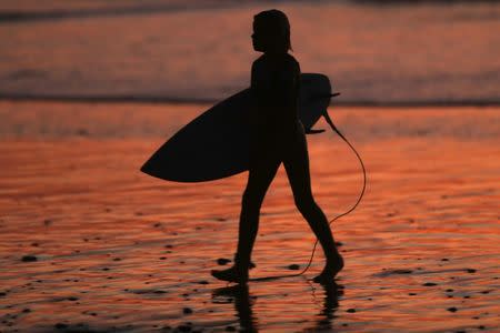 A surfer walks out of the water after sunset in Solana Beach following a record setting day of temperatures according to local media, in Southern California, U.S., October 23, 2017. REUTERS/Mike Blake