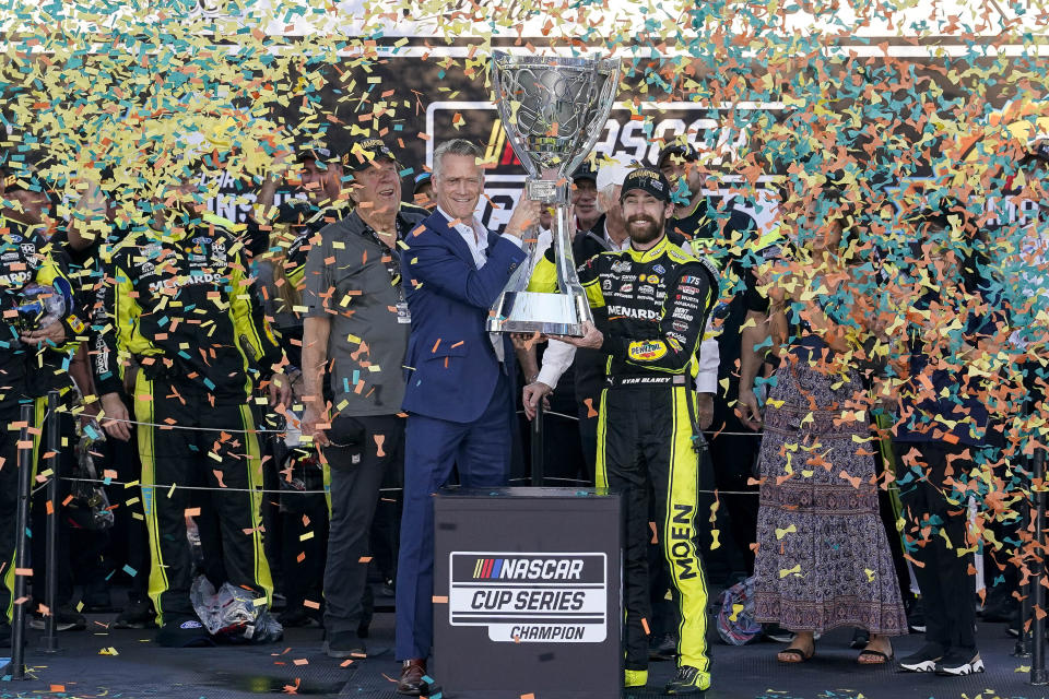 Ryan Blaney, center right, receives the NASCAR Cup Series Championship Cup from NASCAR president Steve Phelps, center left, after winning it at Phoenix Raceway, Sunday, Nov. 5, 2023, in Avondale, Ariz. (AP Photo/Darryl Webb)