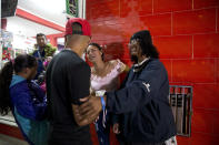 In this Sept. 8, 2018 photo, Sandra Cadiz, right, reunites with her son Leonardo, front left, and her daughter-in-law Daniela Gomez, as she and her 10-year-old daughter Angelis, far left, arrive to the bus station in Lima, Peru, after their long trip from Venezuela. Cadiz immediately noticed that her son and his family looked like they'd gained weight. Angelis, meanwhile, admired her baby niece's sparkling new shoes. (AP Photo/Ariana Cubillos)