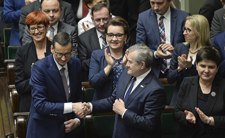 Polish Prime Minister Mateusz Morawiecki, front row left, is applauded by members of his government after winning the confidence vote in the parliament, in Warsaw, Poland, Wednesday, Dec. 12, 2018. Morawiecki’s conservative government easily survived a confidence vote in parliament that the leader had unexpectedly asked for earlier in the day. Morawiecki, with the ruling Law and Justice party, had said he wanted to reconfirm that his government has a mandate from lawmakers as it pushes through its “great reforms.”(AP Photo/Alik Keplicz)