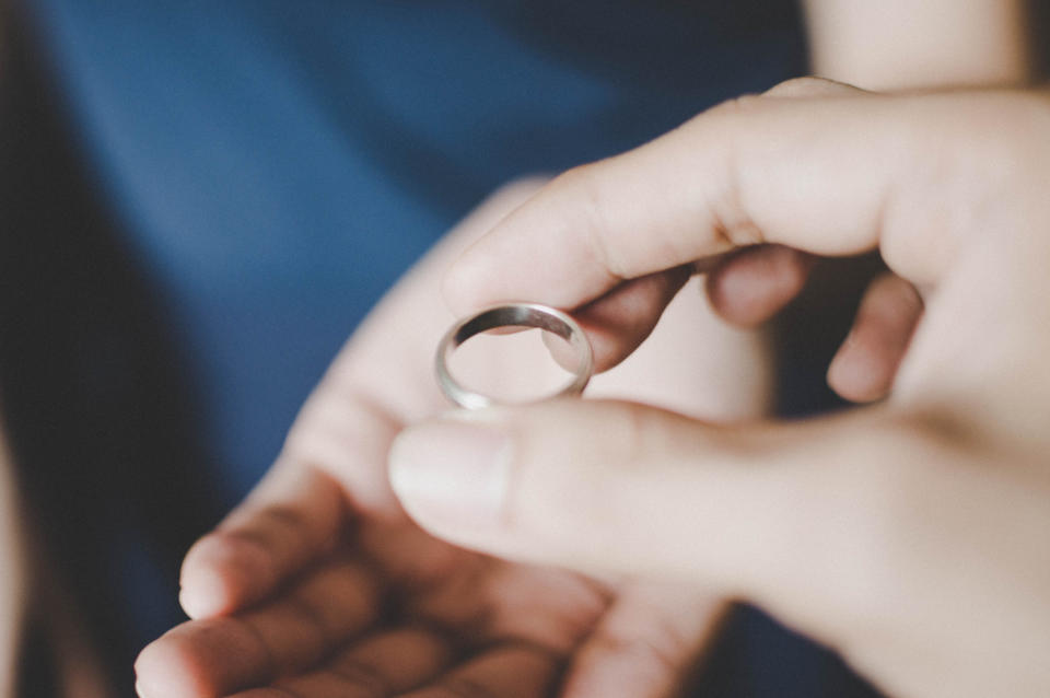 Close-up of a hand holding a silver ring, about to hand it to someone else