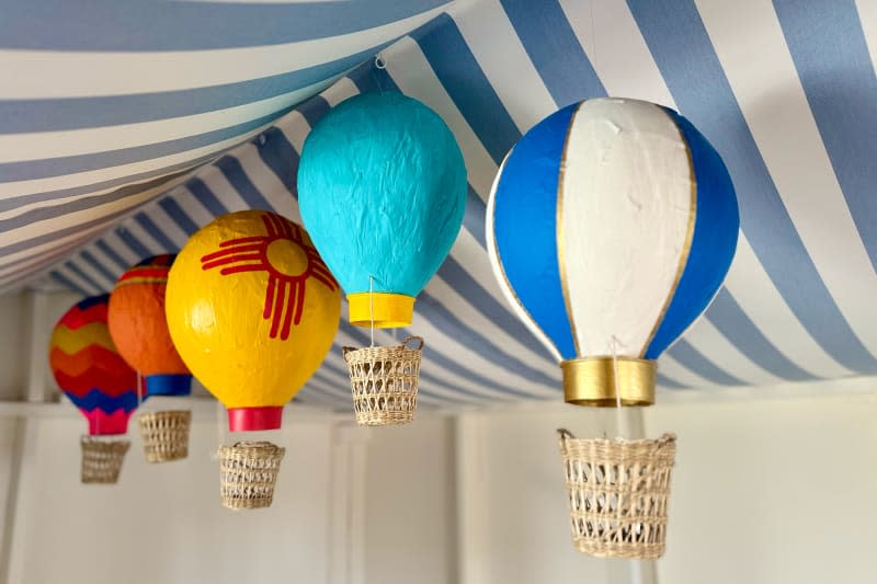 Papier-mâché balloons hanging in tent created in baby nursery.