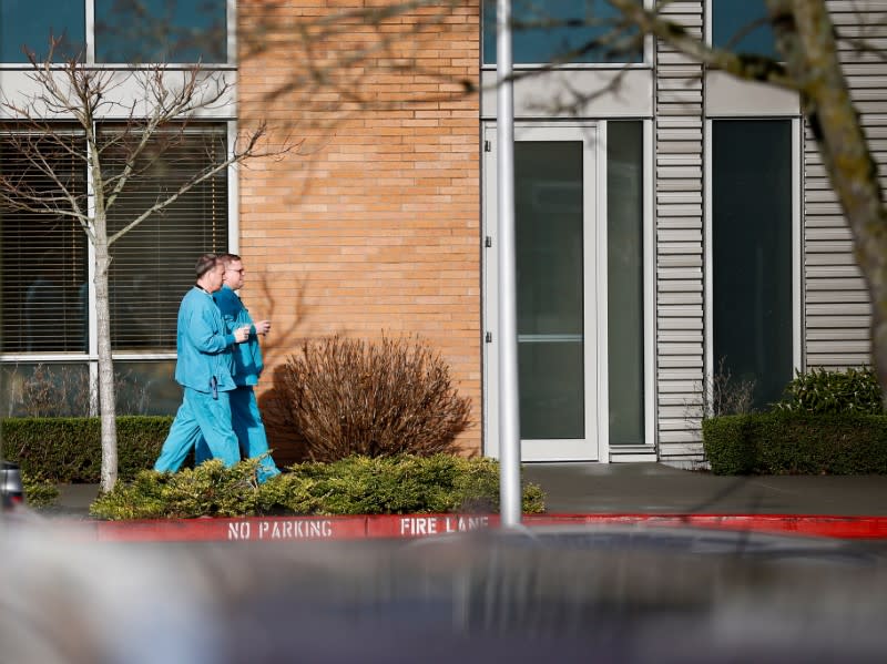 Employees in scrubs walk on the campus at Providence Regional Medical Center after coronavirus victim treated in Everett