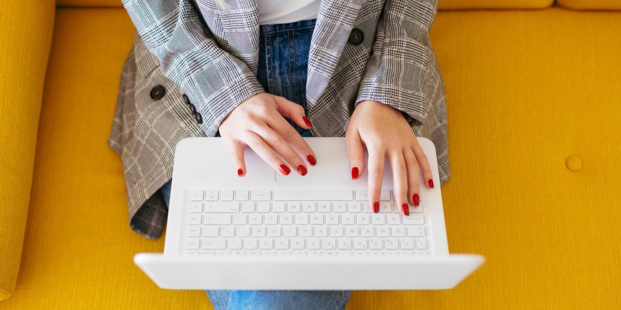 Woman sitting on couch working on laptop