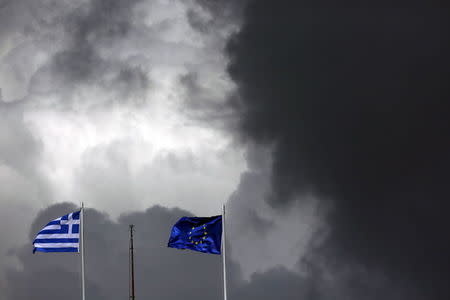 A European Union flag (R) and a Greek national flag flutter atop a building in central Athens March 28, 2015. REUTERS/Kostas Tsironis