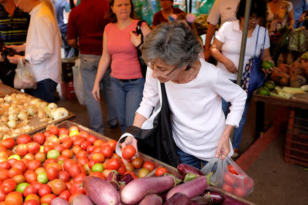 A woman selects tomatoes in a street market in Caracas, Venezuela August 18, 2018. REUTERS/Marco Bello