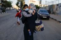 <p>Une Palestinienne transportant son fils? évacue après que leur tour a été touchée par des frappes aériennes israéliennes, dans la ville de Gaza.</p>