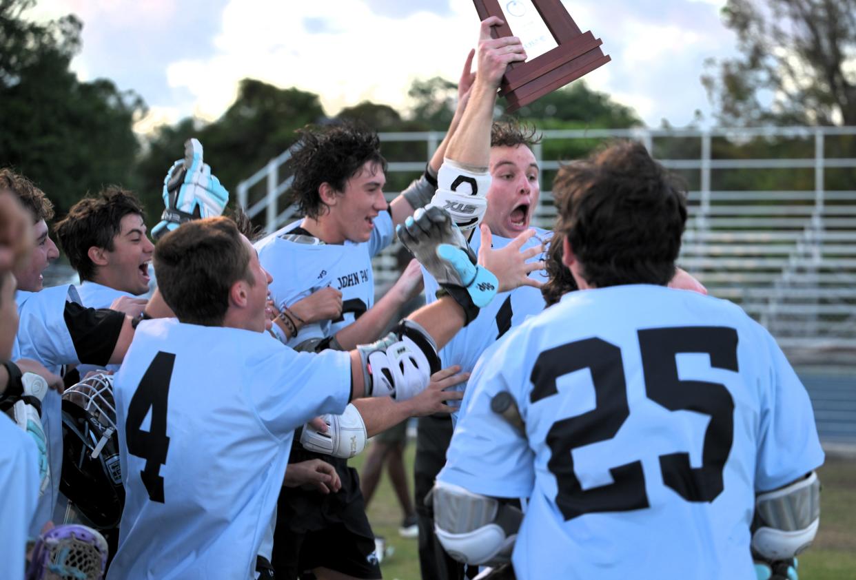 St. John Paul II's Graham McCleneghen with trophy and teammates after a district final win against Oxbridge Academy on April 16, 2024.