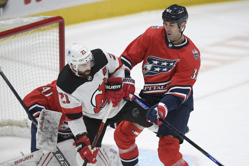 Washington Capitals defenseman Zdeno Chara (33) and New Jersey Devils right wing Kyle Palmieri (21) compete for the puck during the second period of an NHL hockey game Tuesday, March 9, 2021, in Washington. (AP Photo/Nick Wass)