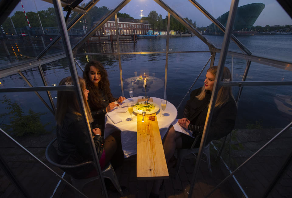 FILE - In this May 5, 2020 file photo, staff at the Mediamatic restaurant serve food to volunteers seated in small glasshouses during a try-out of a setup which respects social distancing abiding by government directives to combat the spread of the COVID-19 coronavirus in Amsterdam, Netherlands. Restaurants around the world try to lure back clientele while keeping them virus-free. (AP Photo/Peter Dejong, File)