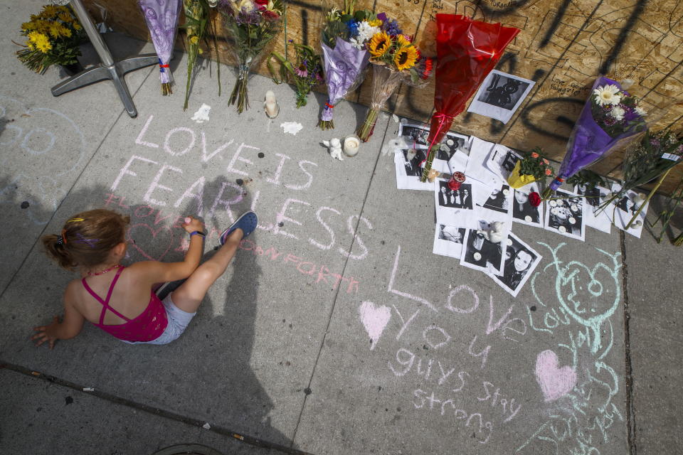A young girl writes a message on the sidewalk at a site remembering the victims of a Sunday evening shooting on Danforth Avenue, in Toronto on Monday, July 24, 2018. (Mark Blinch/The Canadian Press via AP)