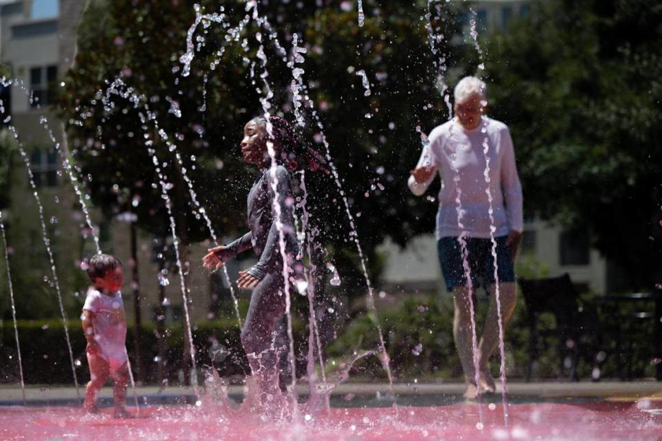 Rancho Cordova resident, Inari Track, 6, center, cools down with Londyn Winston, 18-months, and Hans Gregerson in the water fountain in Village Green Park on Thursday, July 11, 2024, in Rancho Cordova.