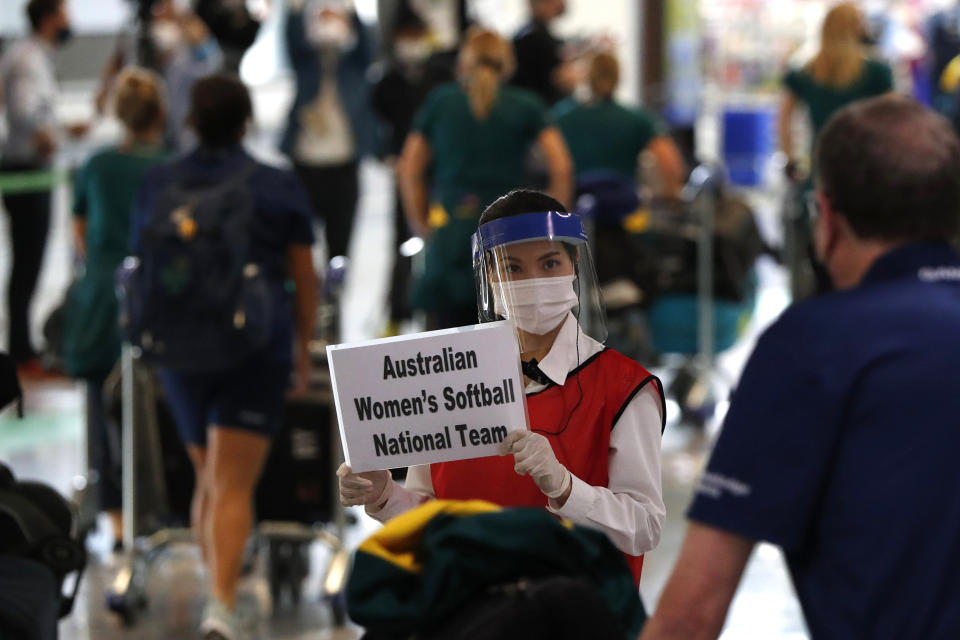 FILE - In this June 1, 2021, file photo, a woman wearing protective mask and face shield greets members of Australia's Olympic softball squad on their arrival at Narita international airport in Narita, east of Tokyo, Japan. The Tokyo Olympics are not looking like much fun: Not for athletes. Not for fans. And not for the Japanese public, who are caught between concerns about the coronavirus at a time when few are vaccinated on one side and politicians and the International Olympic Committee who are pressing ahead on the other. (Issei Kato/Pool Photo via AP, File)