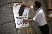 FILE - In this Sept. 1, 2015, file photo, a poster with the logo of Tokyo 2020 Olympic Games is removed from a wall by a worker during an event staged for photographers at the Tokyo Metropolitan Government building in Tokyo. Tokyo Olympic organizers decided to scrap the logo for the 2020 Games following another allegation its Japanese designer might have used copied materials. (AP Photo/Eugene Hoshiko, File)