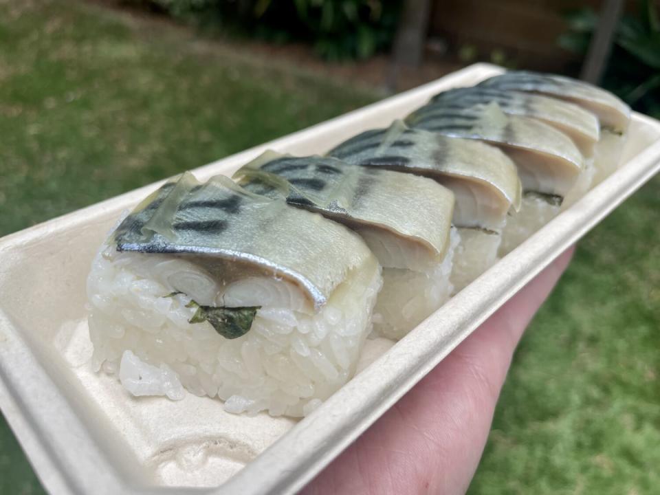 six pieces of sushi in a cardboard container