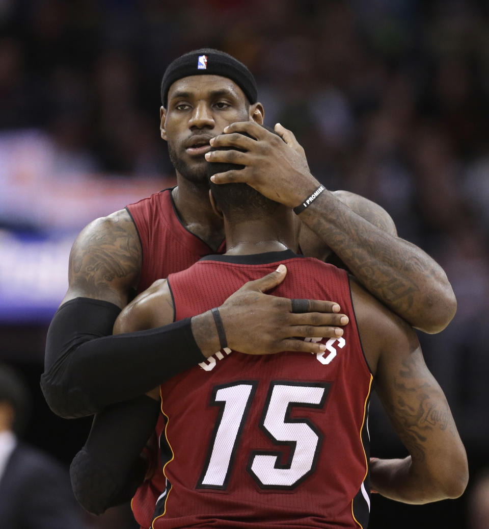 Miami Heat's LeBron James, left, hugs Mario Chalmers during a timeout in the fourth quarter of an NBA basketball game against the Cleveland Cavaliers on Tuesday, March 18, 2014, in Cleveland. Miami defeated Cleveland 100-96. (AP Photo/Tony Dejak)