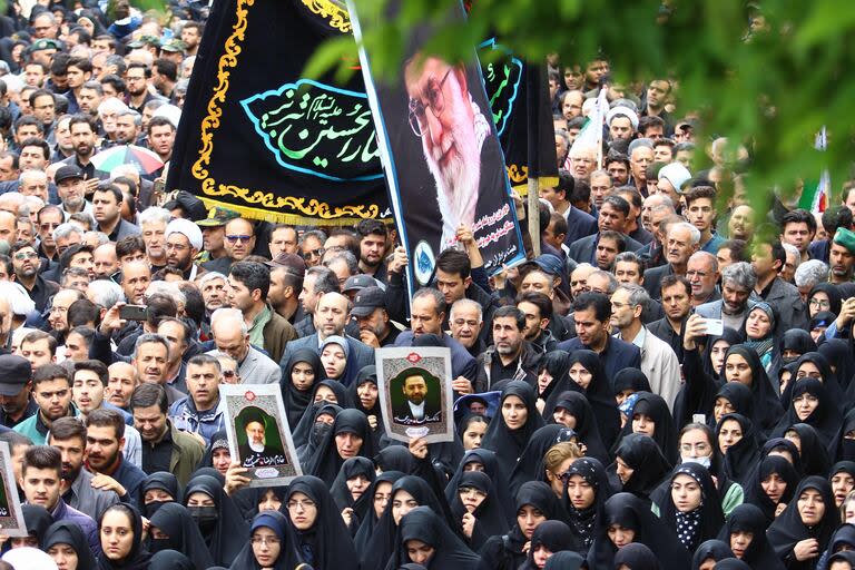 Iraníes portando un retrato del líder supremo de Irán caminan en la procesión fúnebre de Raisi en la ciudad noroccidental de Tabriz