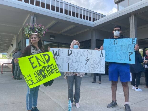 People hold placards against Islamophobia in a vigil outside of Prince George, B.C., city hall on Tuesday in remembrance of the Muslim family of four killed when they were hit by a pickup truck in London, Ont., on June 6. (Andrew Kurjata/CBC - image credit)