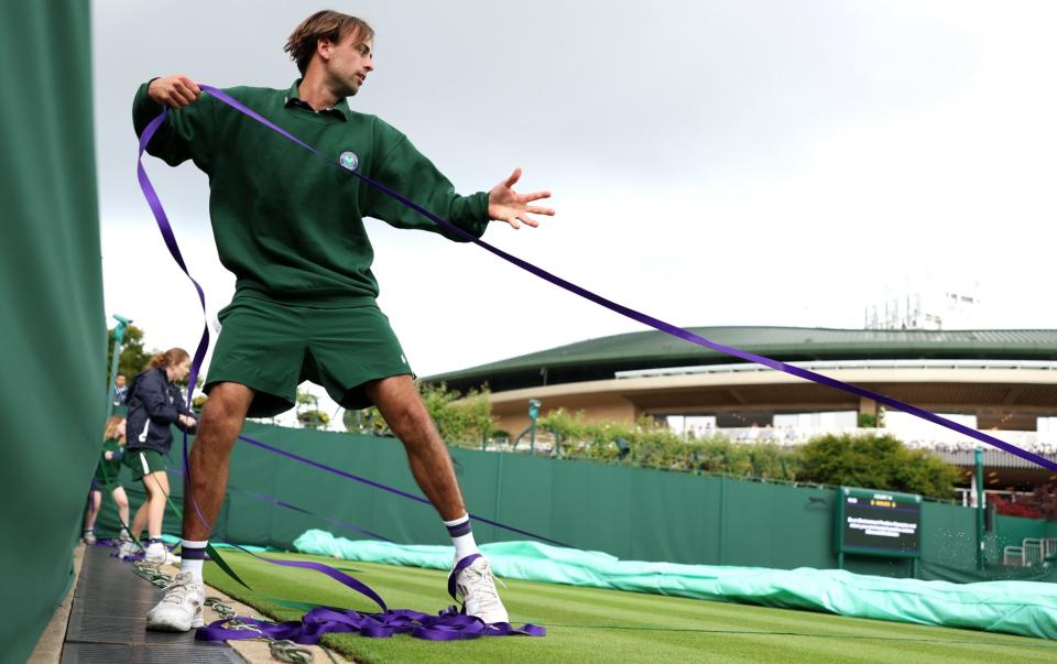 El personal de tierra saca las cubiertas de lluvia durante el tercer día del Campeonato de Wimbledon 2023 en el All England Lawn Tennis and Croquet Club el 5 de julio de 2023 en Londres, Inglaterra