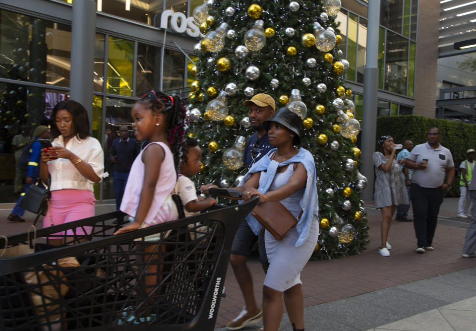 Shoppers pass a Christmas tree at the entrance to the Rosebank Shopping Mall in Johannesburg Saturday, Dec. 23, 2022. South Africa's Christmas 2022 is a start/stop affair because the country's daily power cuts are hitting just about every aspect of the holiday with businesses and families coping with rolling outages of electricity lasting from seven to 10 hours per day. (AP Photo/Denis Farrell)