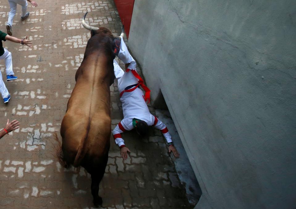 <p>Un morlaco engancha del pantalón a un corredor en pleno callejón a la entrada de la Plaza de Toros (Reuters) </p>