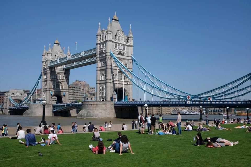 People relax in the hot and sunny weather on the grass beside Tower Bridge (AFP/Getty Images)