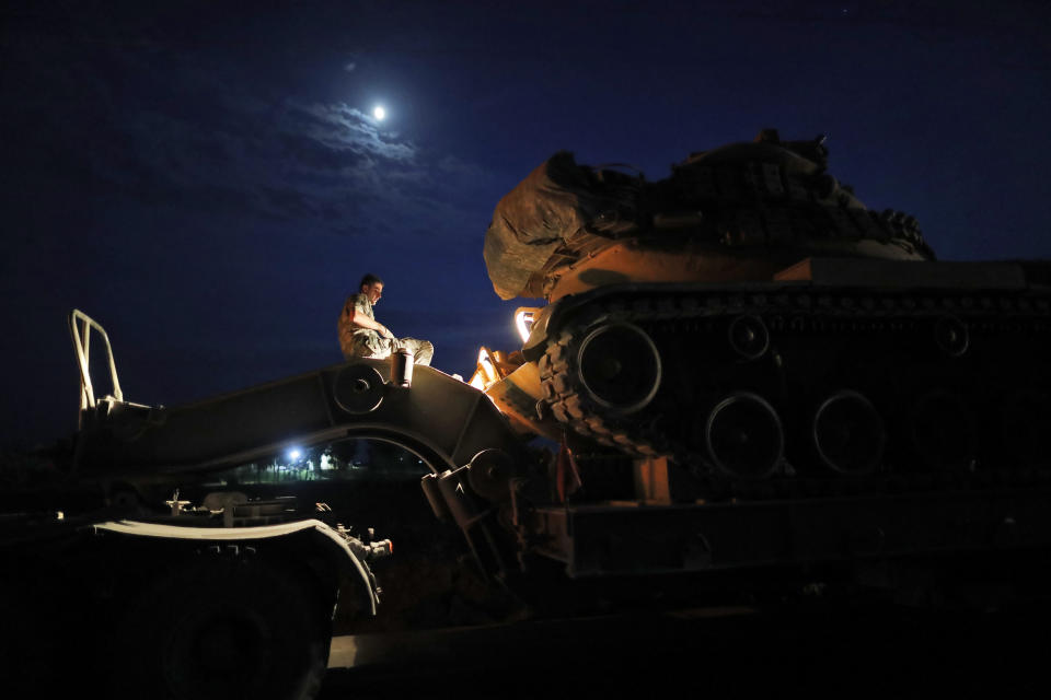 A Turkish army officer prepares to upload a tank from a truck to its new position on the Turkish side of the border between Turkey and Syria, in Sanliurfa province, southeastern Turkey, Tuesday, Oct. 8, 2019. Tensions have risen at the border between Turkey and Syria, on expectation of a Turkish military incursion into Syria. (AP Photo/Lefteris Pitarakis)