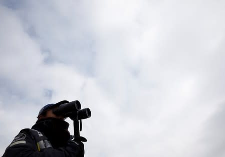 A staff on a whale watching tour boat looks for whales with a binoculars in the sea near Rausu