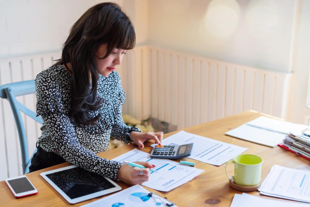 Businesswoman at desk crunching numbers with a calculator 