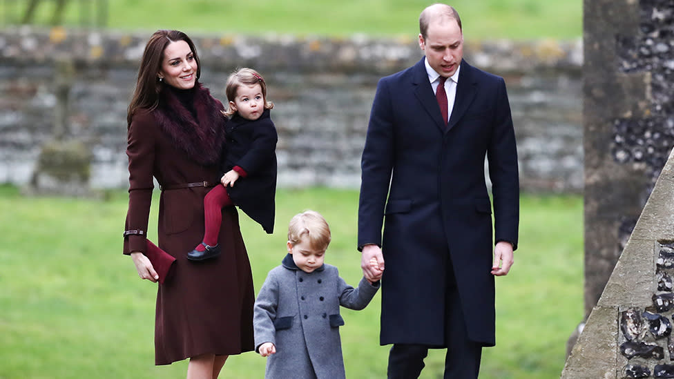 Kate Middleton hold Charlotte while Prince William holds Prince George's hand at Sandringham. 