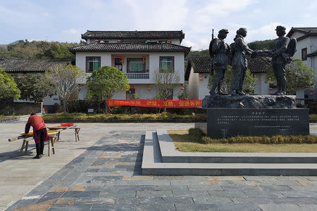 A villager is seen next to a statue depicting Chinese Red Army members and villagers, in Shazhou village, Rucheng county, Hunan province, China December 3, 2018. Picture taken December 3, 2018. REUTERS/Shu Zhang