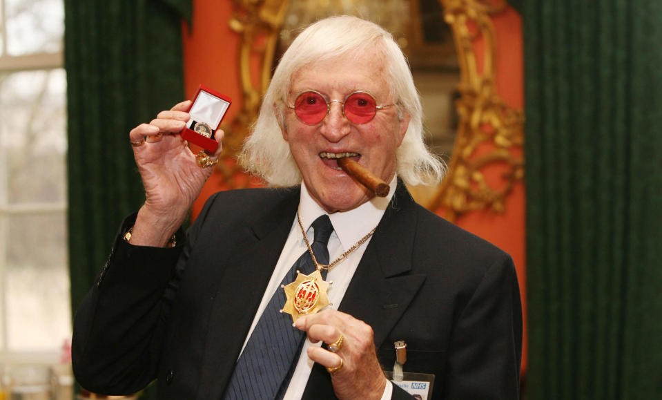 <b>Sir Jimmy Savile (31 October 1926 to 29 July 2011)</b> <br><br>As a renowned DJ, television presenter and charity fundraiser, Sir Jimmy Savile was one of the best-loved British media personalities of the last 50 years. First gaining fame as a DJ and radio host, in 1964 became the inaugural presenter of Top of the Pops. Savile went on to front a series of Public Information Films, including ‘Clunk Click Every Trip’, and later television series ‘Jim’ll Fix It’.<br><br>At the height of its popularity, ‘Jim’ll Fix It’ received 20,000 letters a week from children who wanted Savile to make their dreams come true. It was a far cry from his earlier life as a miner, hospital porter, professional wrestler and dance-hall promoter. He also claimed to have been the world’s first DJ to join two turntables together to play music continuously.<br><br>Aside from his work on television and radio, Savile was a prolific fundraiser – running more than 200 marathons and bringing in £42million for charities over the years. Savile was known for his eccentricity and fashion sense, frequently clad in tracksuits or shell suits with large gold jewellery. He was also a member of MENSA with an IQ of 149. Savile was found dead at his home in Roundhay, Leeds on 29 November three days before his 85th birthday.