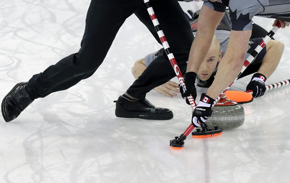 Canada's Ryan Fry, center, delivers the rock while teammates Ryan Harnden, left, and E.J. Harnden, right, sweep the ice, during the men's curling gold medal game against Britain at the 2014 Winter Olympics, Feb. 21, 2014, in Sochi, Russia. 