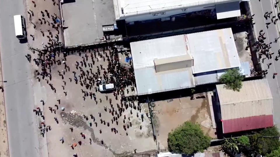 People gather near a building, amid reports of widespread looting and arson as police and the public sector protest over a pay cut that officials blamed on an administrative glitch, in Port Moresby (MACKENZIE WAIDE via REUTERS)