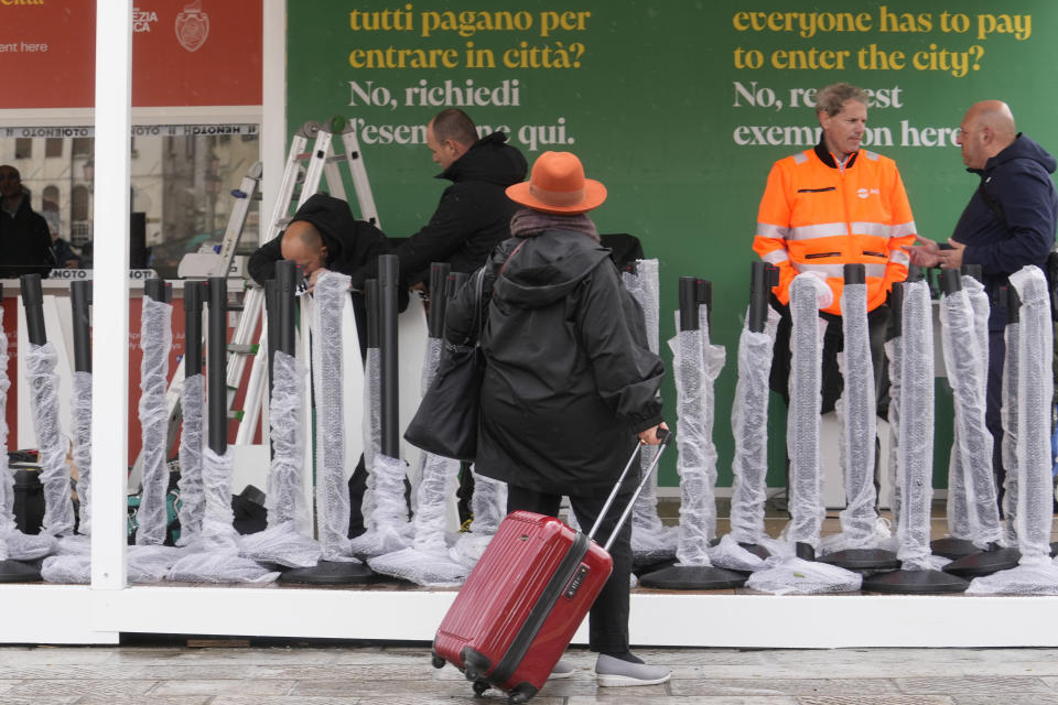 Workers prepare the tourist tax cashier desks outside the main train station in Venice, Italy, Wednesday, April 24, 2024. The lagoon city of Venice begins a pilot program Thursday, April 25, 2024 to charge daytrippers a 5 euro entry fee that authorities hope will discourage tourists from arriving on peak days. Officials expect some 10,000 people will pay the fee to access the city on the first day, downloading a QR code to prove their payment. (AP Photo/Luca Bruno)