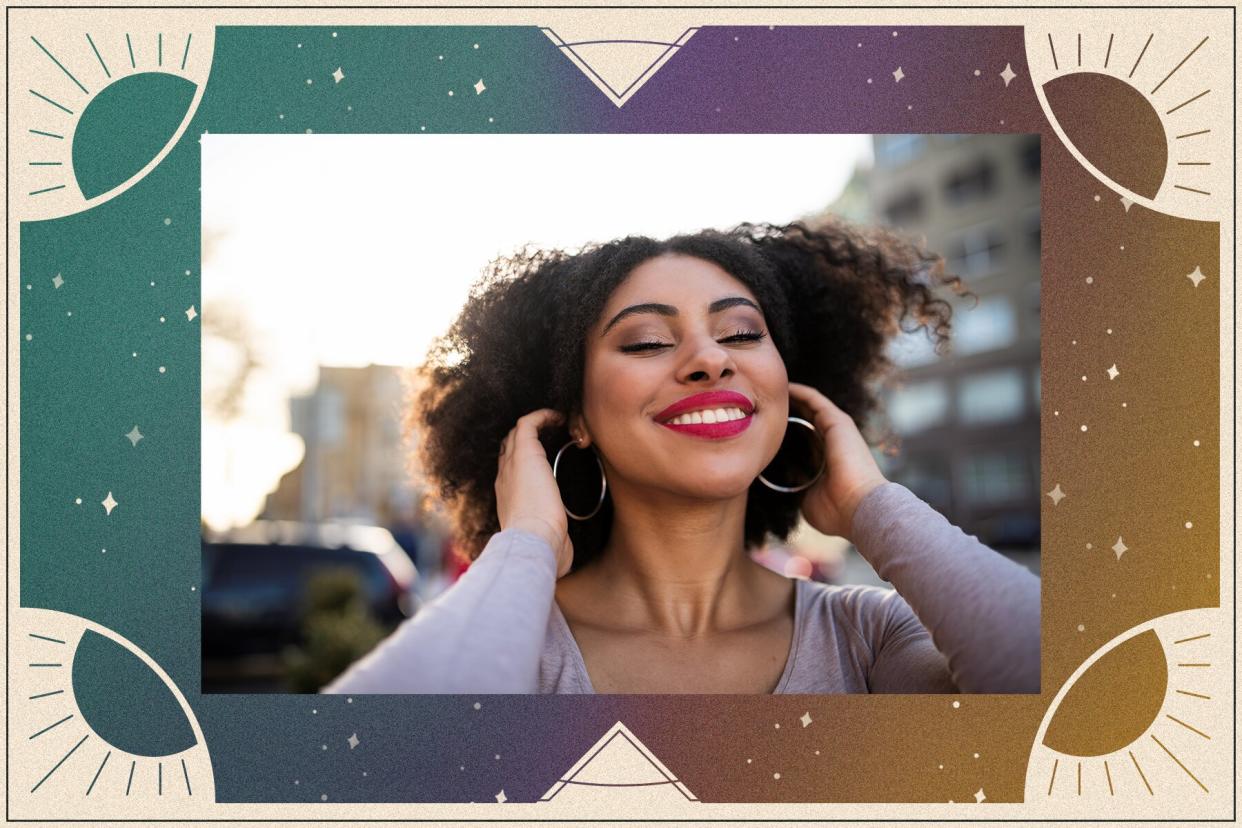 Woman smiling with her eyes closed and hands in her hair.