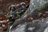 In this Thursday, Dec. 13, 2018 photo, Israeli soldiers stand guard at the site of their excavation work, near the southern border village of Mays al-Jabal, Lebanon. As Israeli excavators dig into the rocky ground, Lebanese across the frontier gather to watch what Israel calls the Northern Shield operation aimed at destroying attack tunnels built by Hezbollah. But Lebanese soldiers in new camouflaged posts, behind sandbags, or inside abandoned homes underscore the real anxiety that any misstep could lead to a conflagration between the two enemy states that no one seems to want. (AP Photo/Hussein Malla)