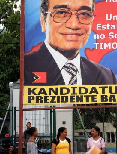 Local residents are seen standing in front of a banner of presidential candidate Francisco "Lu Olo" Guterres in Dili. Former military commander Taur Matan Ruak was ahead in an early count for East Timor's presidential run-off vote on Monday, according to the elections secretariat