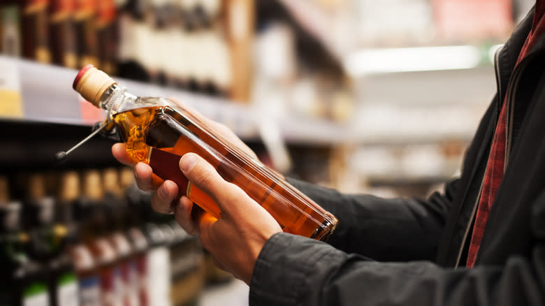 man examines whiskey bottle