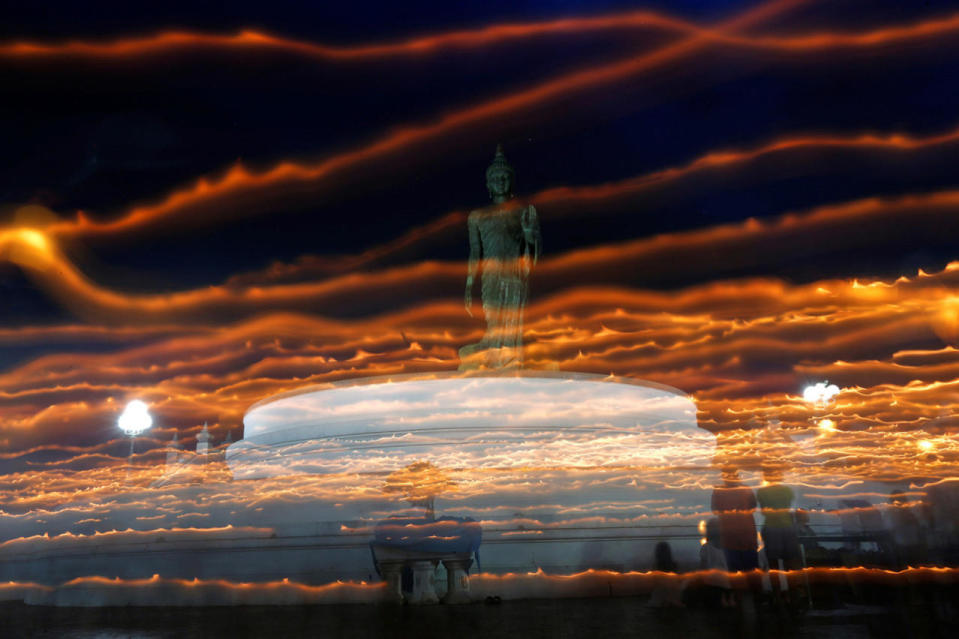 Buddhists carry candles at a temple in Nakhon Pathom