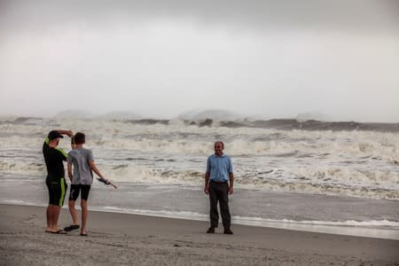 Aurel Paluca, Anton Lekaj, and Ded Paluca take photos by the shore while Hurricane Dorian passes in Jacksonville, Florida