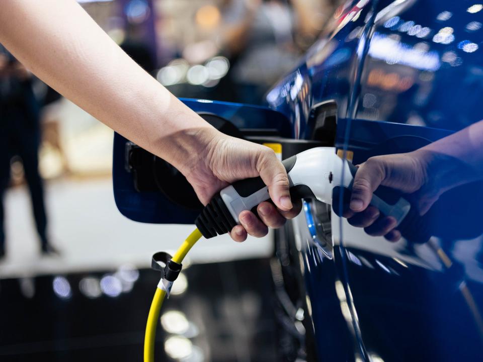A close up of a hand recharging an electric car