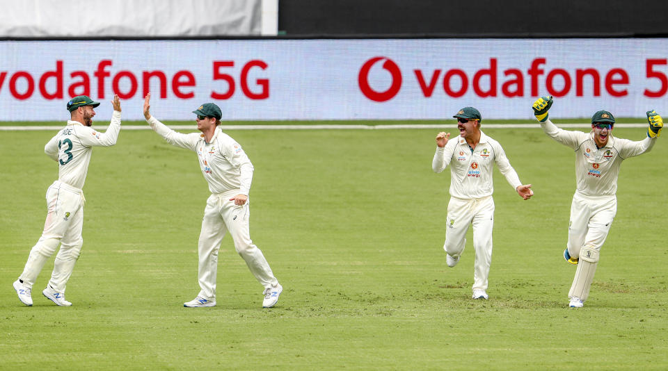 Australia's Matthew Wade, left, is congratulated by teammate Steve Smith on a catch to dismiss India's Ajinkya Rahane as David Warner and Tim Paine react during play on day three of the fourth cricket test between India and Australia at the Gabba, Brisbane, Australia, Sunday, Jan. 17, 2021. (AP Photo/Tertius Pickard)